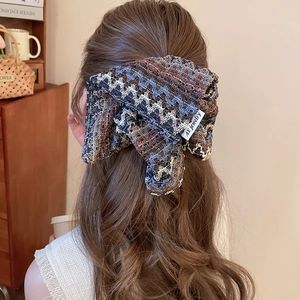 Détail d'un bandeau en maille aux motifs de vagues bleu marine et marron sur cheveux
