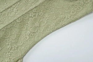 Dettaglio ravvicinato del pizzo floreale e del ricamo delicato sul vestito verde