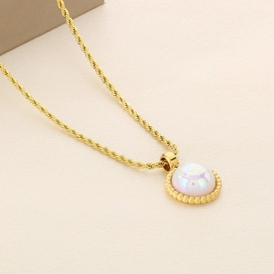 Close-up of golden twist chain necklace with a pearlescent white circular shell pendant