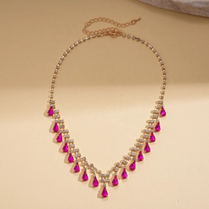 Detailed view of luxury gold necklace with magenta teardrop tassels and crystals