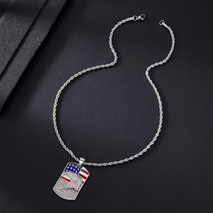 Close-up of silver dog tag pendant with American flag, eagle relief and clear rhinestones