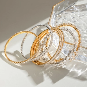 Macro shot of stacked gold and silver stainless steel bangles with zircon inlay detail