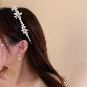 Detail view of cream white pearl floral headband and matching earrings on a model