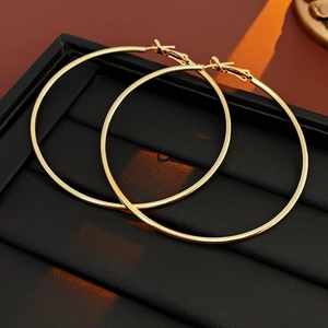 Macro view of large golden hoop earrings placed on a black textured jewelry tray