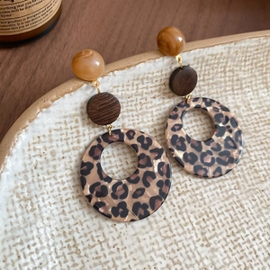 Close-up of leopard print resin earrings with dark brown wood and round beads