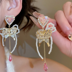 Detail of butterfly drop earrings with pink heart stones and pearl tassels on a model