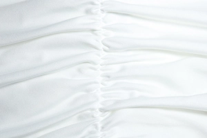 Macro shot of the white pleated fabric with intricate ruched detailing and fine texture