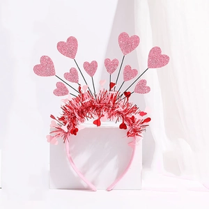 Pink heart headband with glitter accents on white display pedestal with soft draped background
