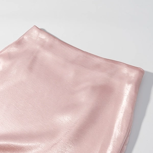 Détail de la taille d'une mini-jupe en satin rose avec texture de tissu soyeux