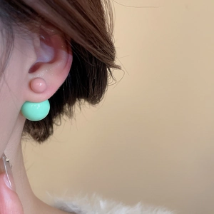 Detailed close-up of double-ball resin earrings with pink and mint green glossy finish