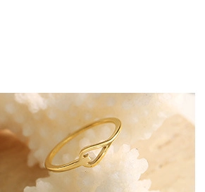 Vue détaillée d'une bague dorée en forme de U avec nœud sur un support de corail