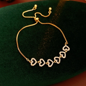 Détail du bracelet cœur en zircon doré avec cinq breloques étincelantes sur velours
