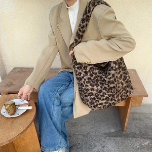 Lifestyle shot of large leopard print faux shearling tote bag on model's shoulder