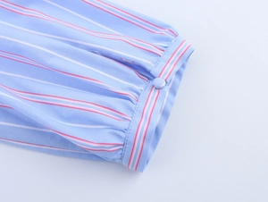 Detail of light blue striped shirt cuff with button closure and pleated fabric texture