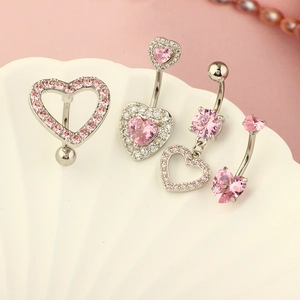 Macro shot of silver navel rings with pink heart crystals on a white shell background