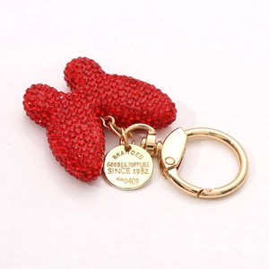 Sparkling red rhinestone bow keychain with golden hardware and engraved round metal tag