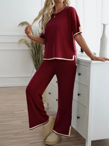 Detail of burgundy knitted set featuring short sleeve top and wide leg pants with beige trim