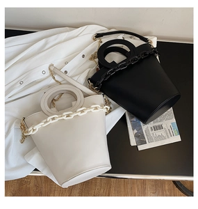 Close-up of stylish bucket bags with thick plastic chains and round top handles