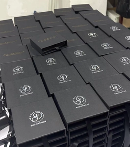 Vista detallada de cajas de joyería negras apiladas con elegantes asas de cinta