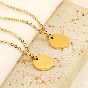 Minimalist gold round alphabet A necklace with fine chain on natural stone background