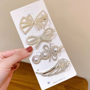 Close-up of four-piece gold hair clip set featuring pearls, rhinestones, and bows