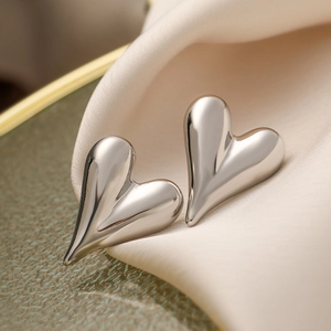 Pendientes de corazón plateados minimalistas sobre seda suave y cristal texturizado