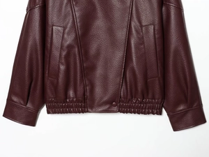 Détail de la veste en PU bordeaux avec texture grainée et finition élastique à l'ourlet
