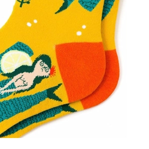 Detail of yellow cotton socks featuring green mermaid pattern and orange heel stitching