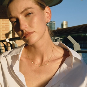Gros plan d'un collier étoile doré et boucles turquoise portés sous la lumière du soir