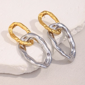 Detailed shot of hammered 18K gold and silver link earrings on a textured stone surface