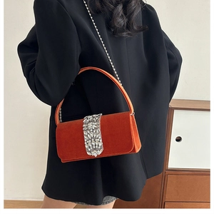 Detail of orange velvet evening bag with sparkling rhinestone buckle and thin chain strap
