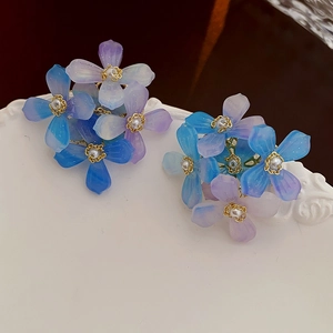 Détail macro de boucles d'oreilles fleurs en acrylique dégradé bleu-violet et perles