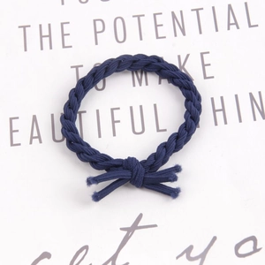 Detail of hand-woven dark blue braided elastic hair tie with knotted texture design