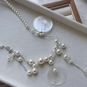 Macro shot of faux pearls and iridescent shell discs on a silver chain necklace