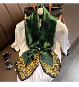 Détail du foulard en soie verte élégant avec bord léopard et motif floral sur chemise blanche