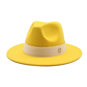 Detailed close-up of yellow wool fedora hat with beige ribbon and golden metal M logo