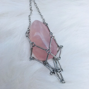 Detailed close-up of pink quartz in silver cage pendant with metallic tassels