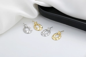 Detail of minimalist 18K gold and silver earrings with irregular hammered metal texture
