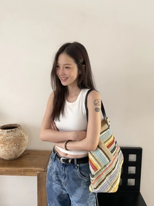 Detail of multi-color striped woven tote bag with premium black leather handles