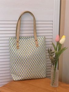 Gros plan d'un sac cabas en toile à motifs géométriques avec poignées en cuir marron