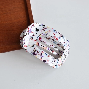 Detailed macro view of white acetate hair claw clip with colorful terrazzo ink pattern