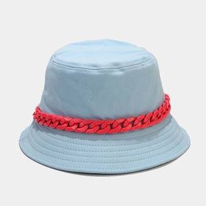 Dettaglio di un cappello a secchiello in cotone azzurro con catena decorativa in plastica rossa