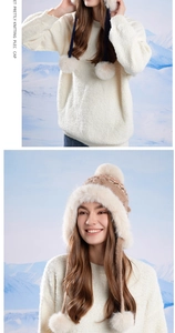 Close-up of winter knit Fair Isle hat with white faux fur lining and plush pom-poms