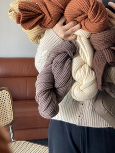 Close-up of assorted thick knitted scarves in beige, camel and deep brown tones