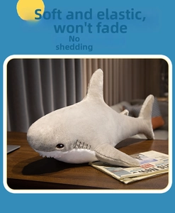 Detail of soft shark plush toy showing grey and white short fur texture on wooden desk