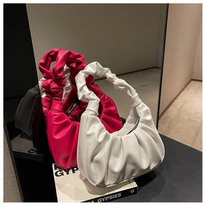 Detailed close-up of pleated leather shoulder bags in bright pink and white colors