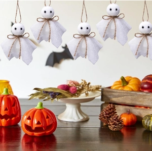 Detailed view of small fabric hanging ghosts with twine bows and pumpkin decorations