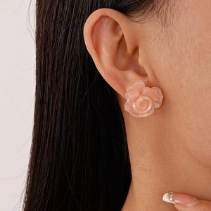 Close-up of a sweet pink resin rose earring worn on a model's ear for size reference