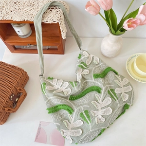 Dettaglio di ricamo floreale 3D su borsa tote in tela verde con decorazioni rustiche