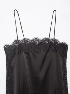 Détail d'un caraco en satin noir avec bordure en dentelle délicate et fines bretelles